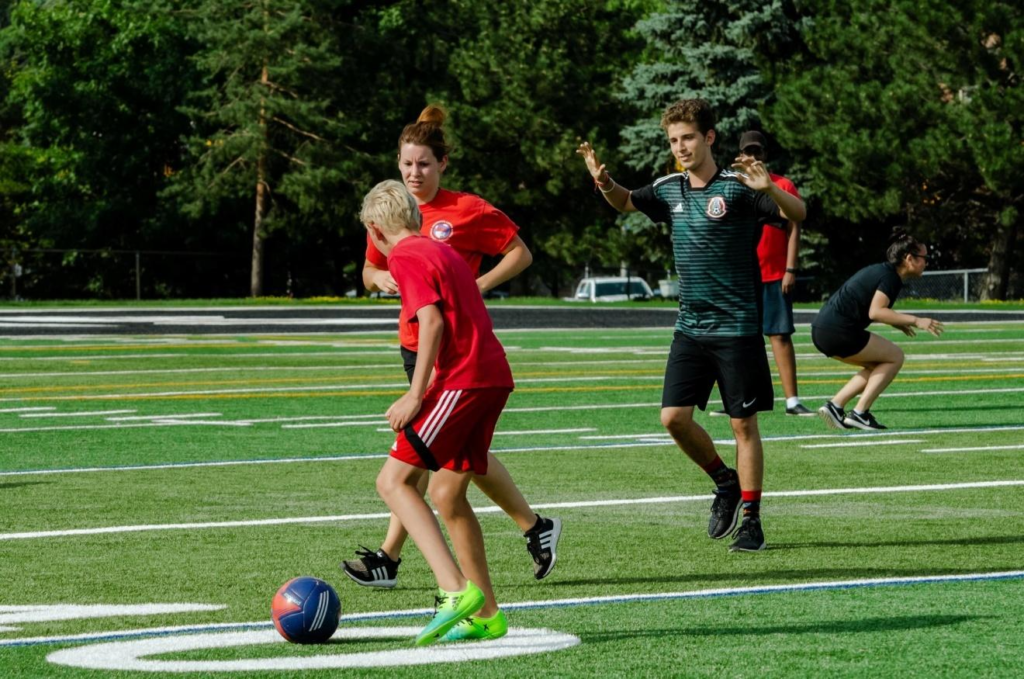 Étudiant et animateurs jouant au soccer au camp d’été linguistique Pilgrim à Ottawa.