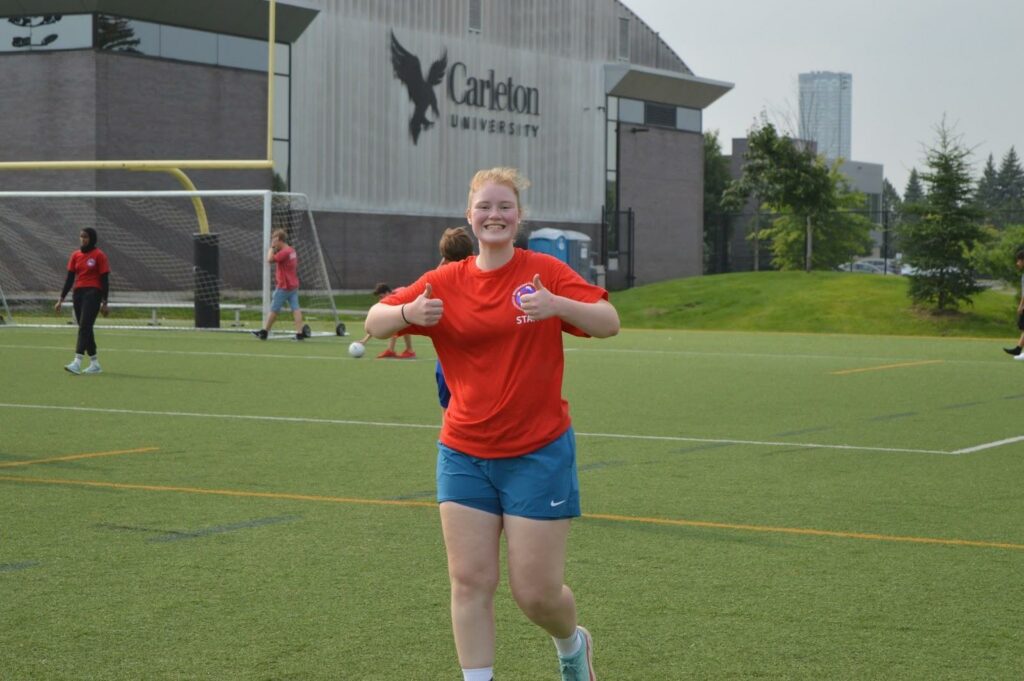 Jeune fille dans un match de foot qui a suivi des cours d'été pour apprendre l'anglais au Camp Pilgrim